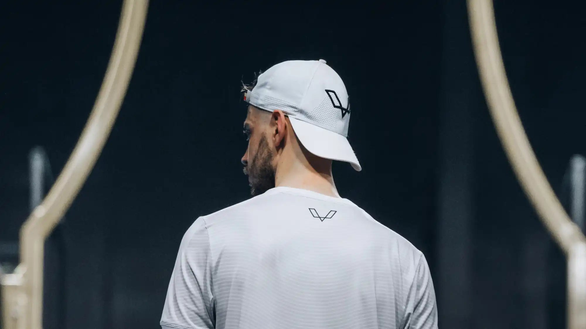 Person wearing a white baseball cap and white t-shirt with a logo on the back.