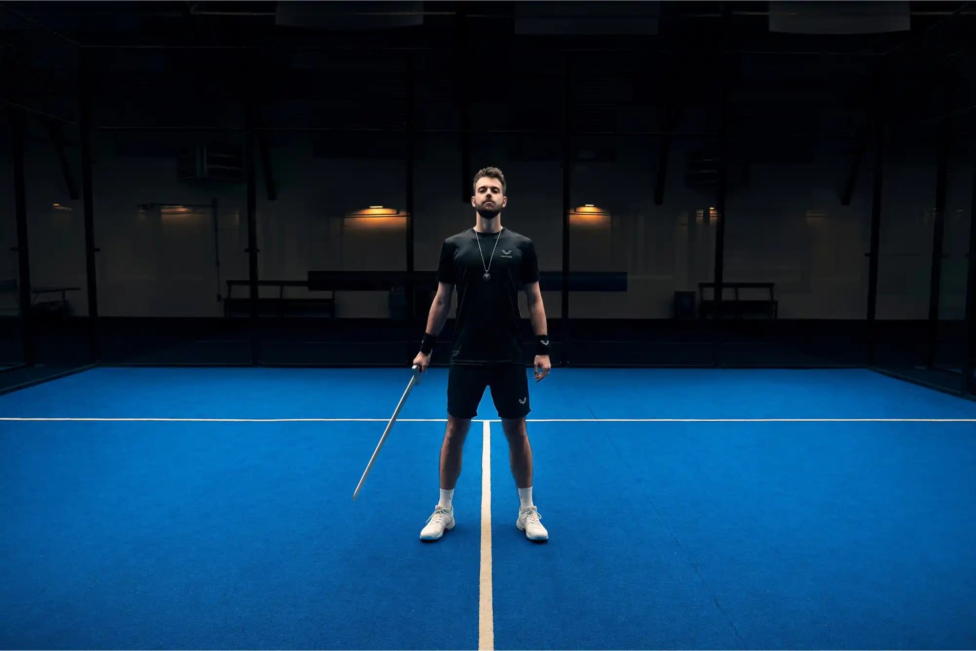 Tennis player standing on a court line while holding a racquet.